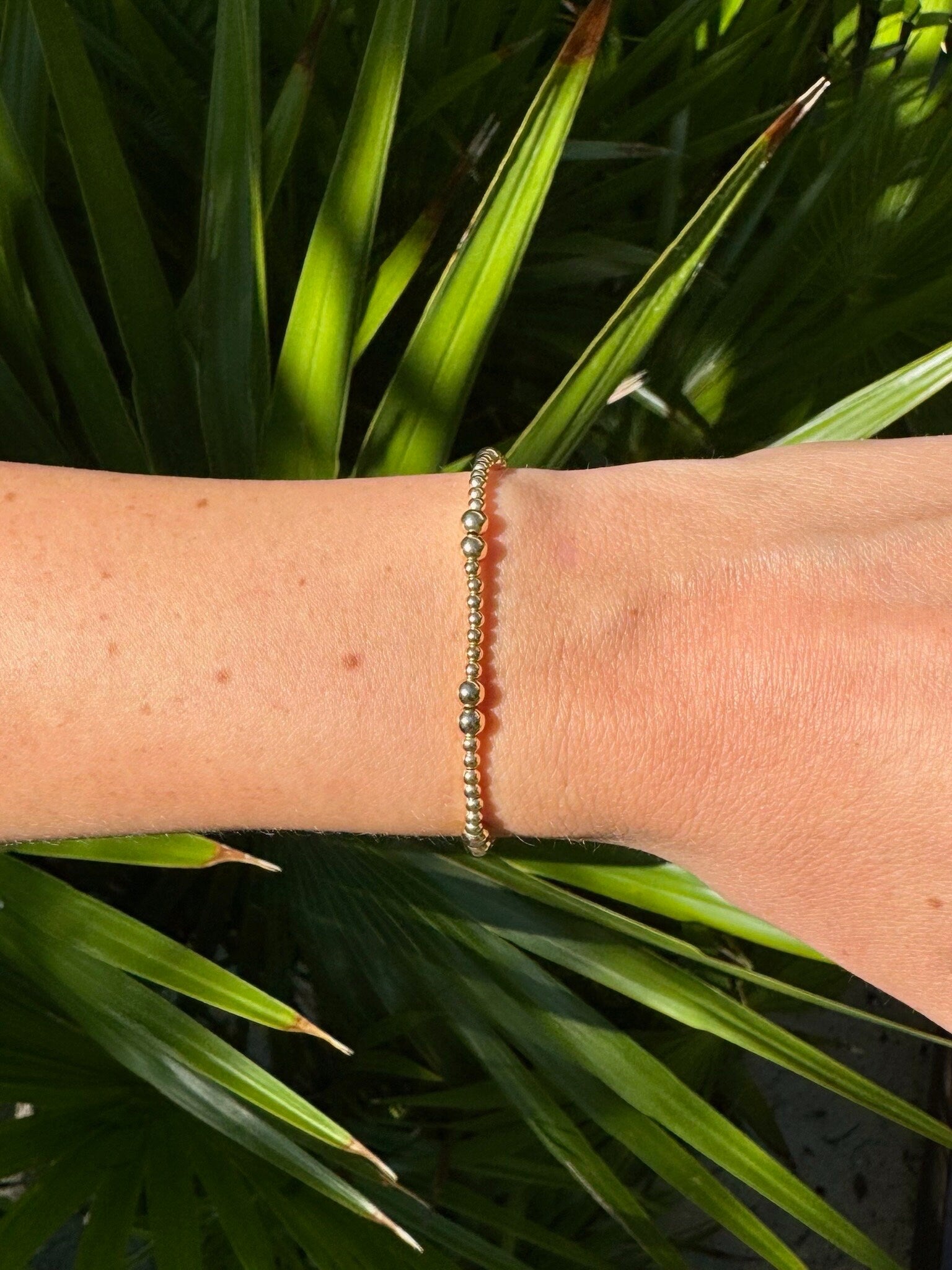 May include: A gold beaded bracelet