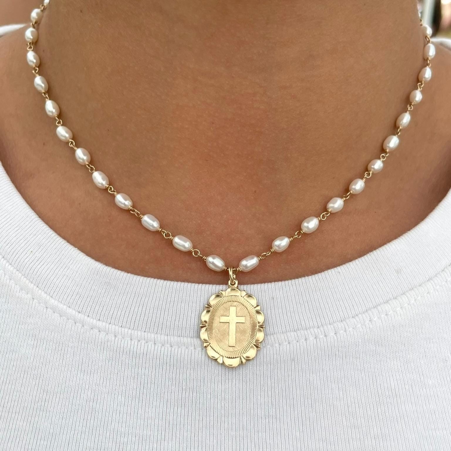 Pearl necklace with a gold pendant worn by a person on a white background
